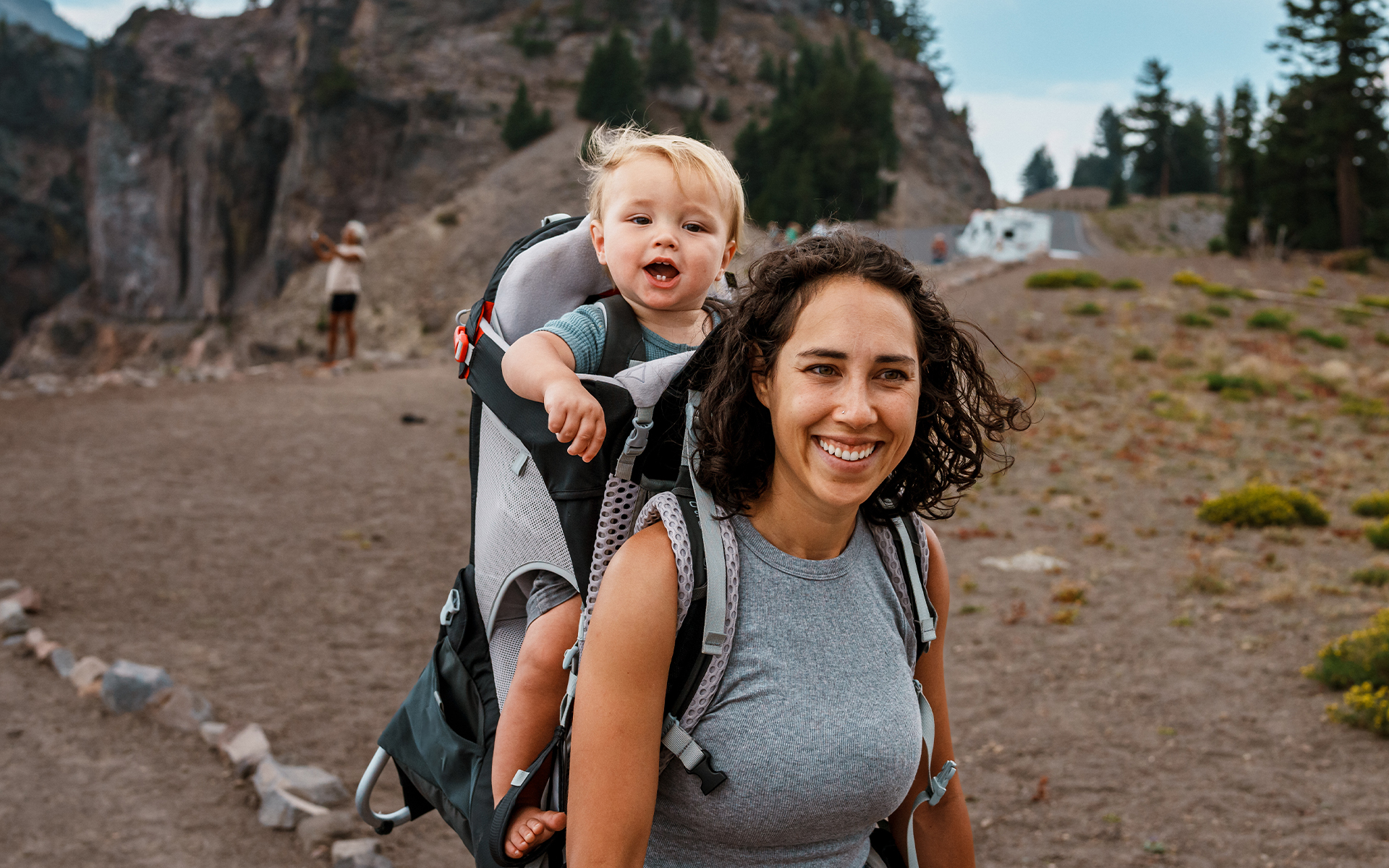 Young boy sitting on Woman's shoulders in a rocky, outdoor park setting.